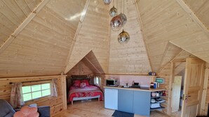 A cozy cabin interior with a loft bedroom, kitchenette, and a seating area with a sofa and rug. - Kota Finlandais Deux Extensions Pour 4 Personnes, Tout Confort (Vignot)