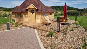 A small wooden cabin with a sloped roof, a wooden deck, and a weather vane. - Kota Finlandais Deux Extensions Pour 4 Personnes, Tout Confort (Vignot)