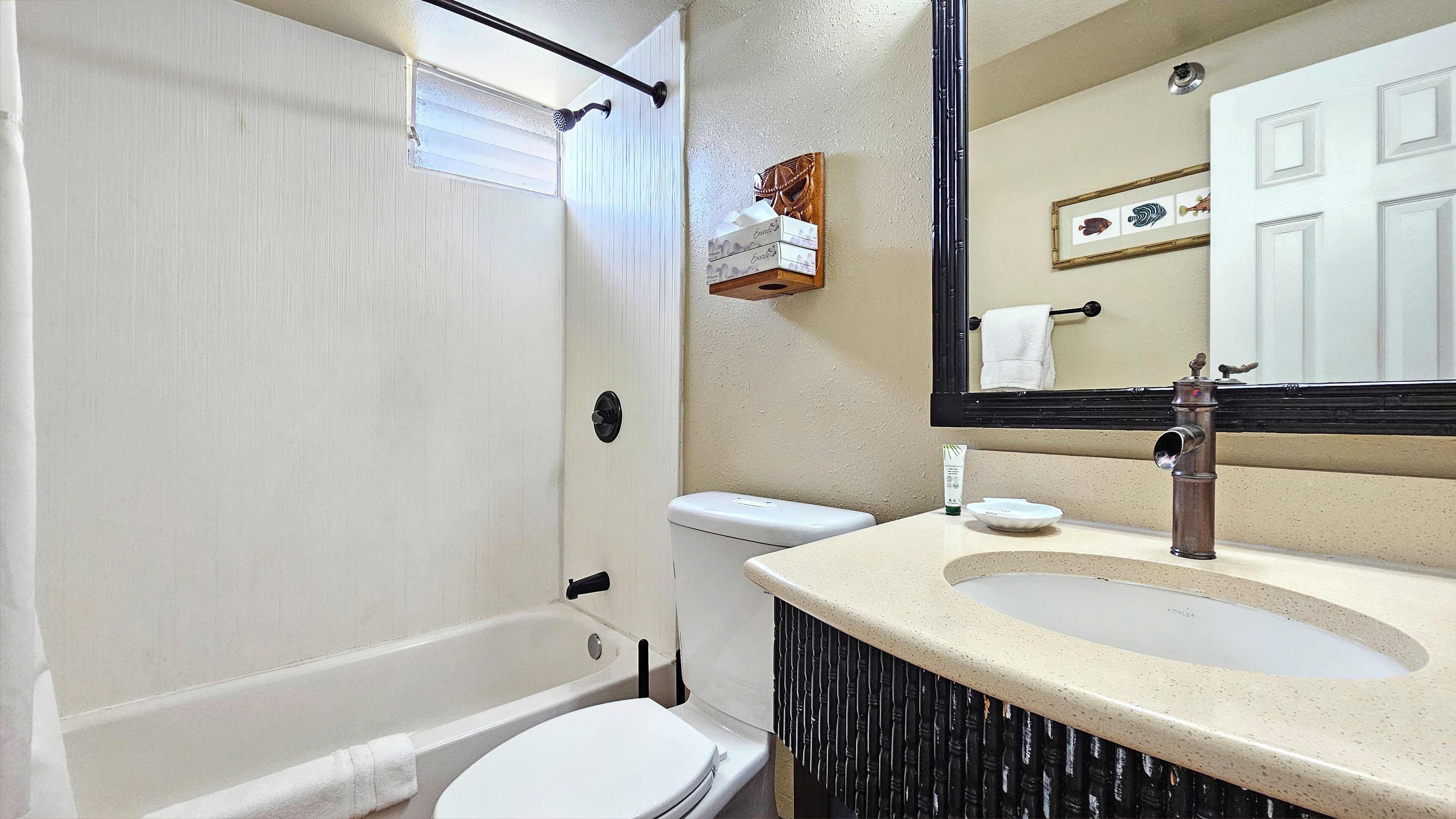 A bathroom with a bathtub, toilet, sink, and a mirror.