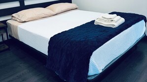 A neatly made bed with a black headboard, a white mattress, and a blue blanket. - Golden Pond Cabins (Altmar)