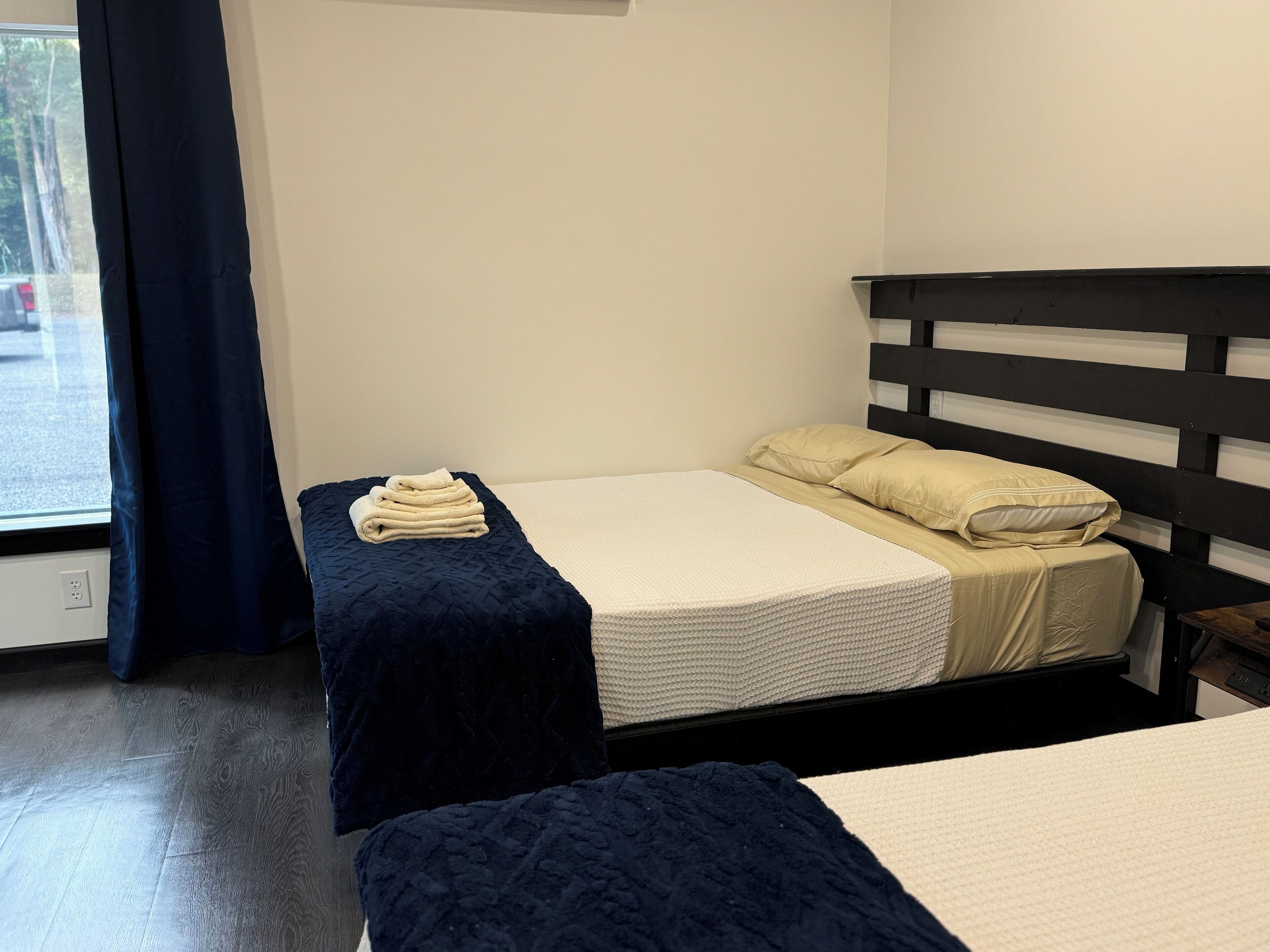 Una habitación con dos camas, una ventana con cortinas y vistas al exterior.