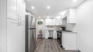 Une cuisine moderne avec des armoires blanches, des appareils en acier inoxydable et un plancher en bois.