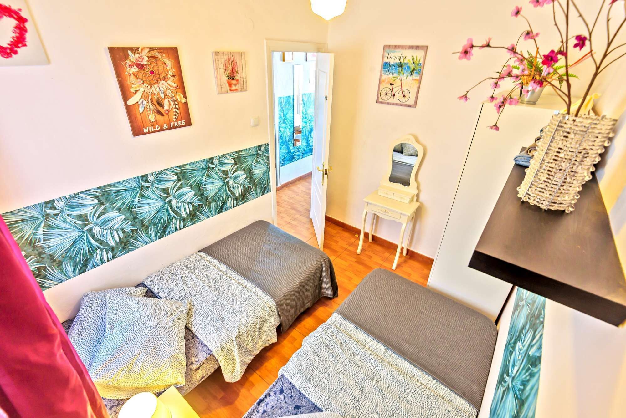Une pièce confortable avec deux lits, une petite table et une chaise. Les murs sont décorés de tableaux et il y a une fenêtre avec vue.