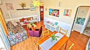 A living room with a sofa, chairs, a dining table, and a TV.
