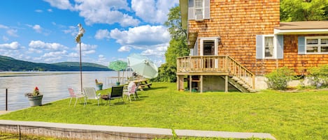 A wooden house with a balcony, a grassy yard, and a lake view.