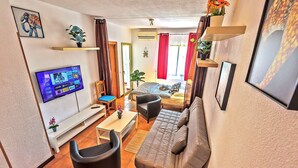 Una sala moderna con sofá, sillones, televisor y comedor.