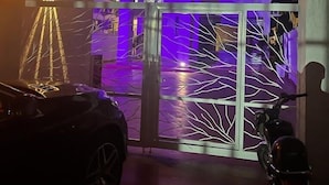 Un bâtiment à l’architecture moderne, doté d’une grande porte en verre et d’un balcon éclairé de lumières violettes.