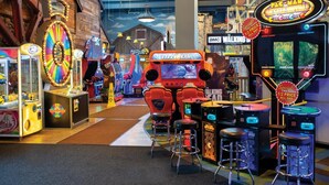 An indoor arcade with various gaming machines, including a Typhoon arcade game, and stools for seating. - 2 Bedroom Deluxe Suite in Great Smokies Lodge! (Sevierville)