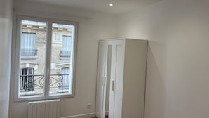 A room with a large window, white wardrobe, and a radiator.
