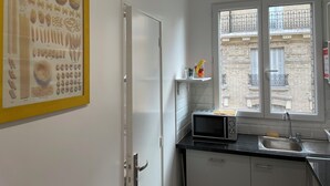 A modern kitchen with a microwave, sink, and a window with a view of a building.
