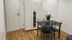 A dining area with a black table and chairs, a white wardrobe, and a wooden floor.