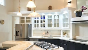 A modern kitchen with white cabinets, a central island, stainless steel appliances, and pendant lighting. - Spacious & Modern Pāhoa Retreat Near Kehena Beach! (Pahoa)