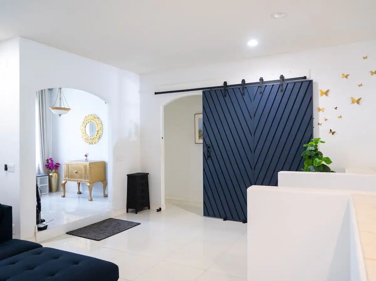 Ein modernes Wohnzimmer mit einer Schiebetür, einem Sofa, einem Couchtisch und einer Wand mit Schmetterlingsaufklebern.