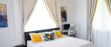 A bedroom with a bed, a desk, and a chair.