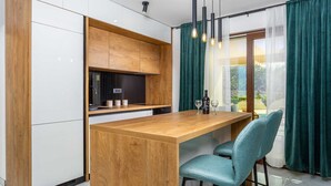 A modern kitchen with wooden cabinets, a central island, and teal chairs. - Villa Loni with Pool & Seaview (Bajčići (Krk))