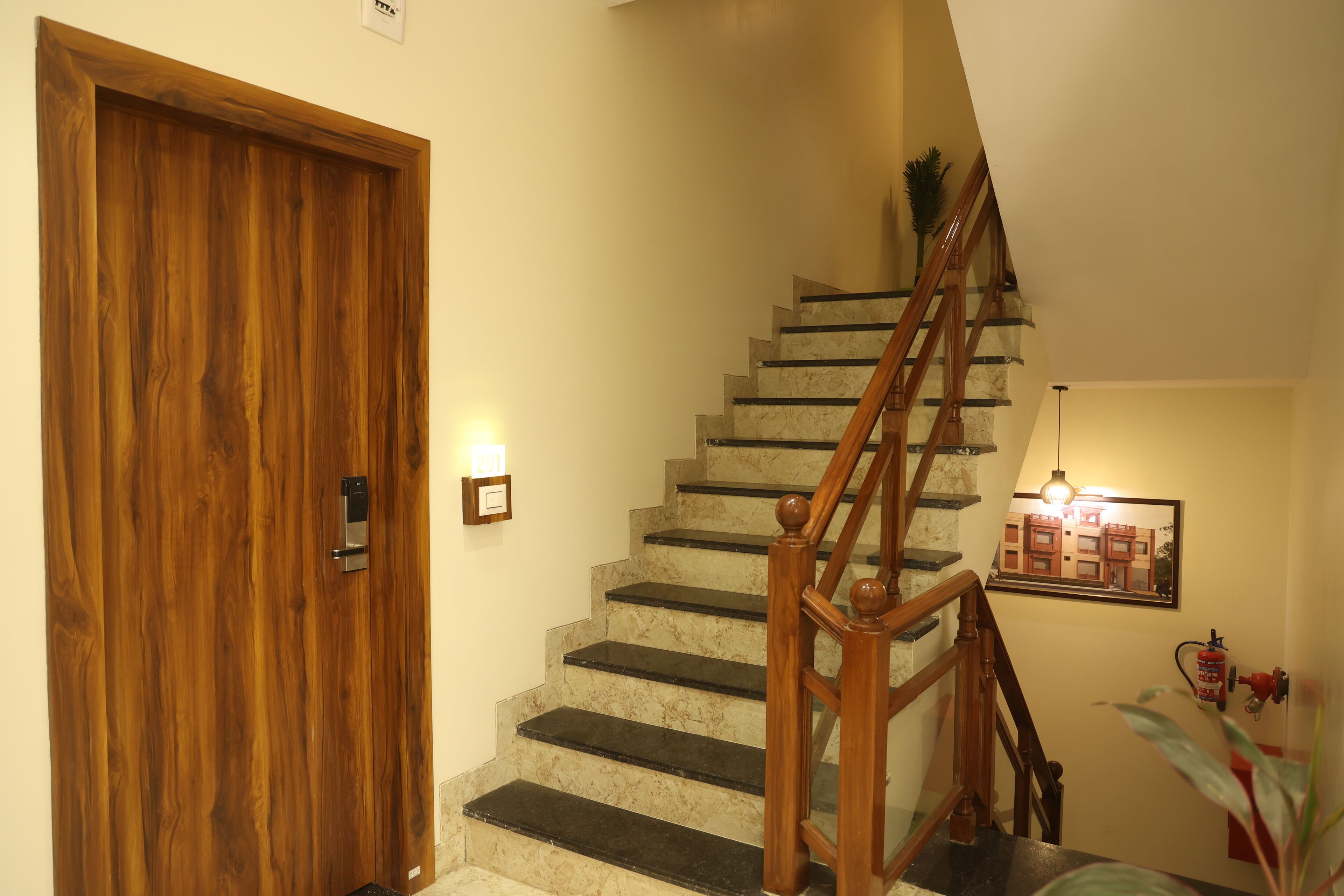 A wooden door, a marble staircase with a wooden handrail, and a framed picture on the wall.