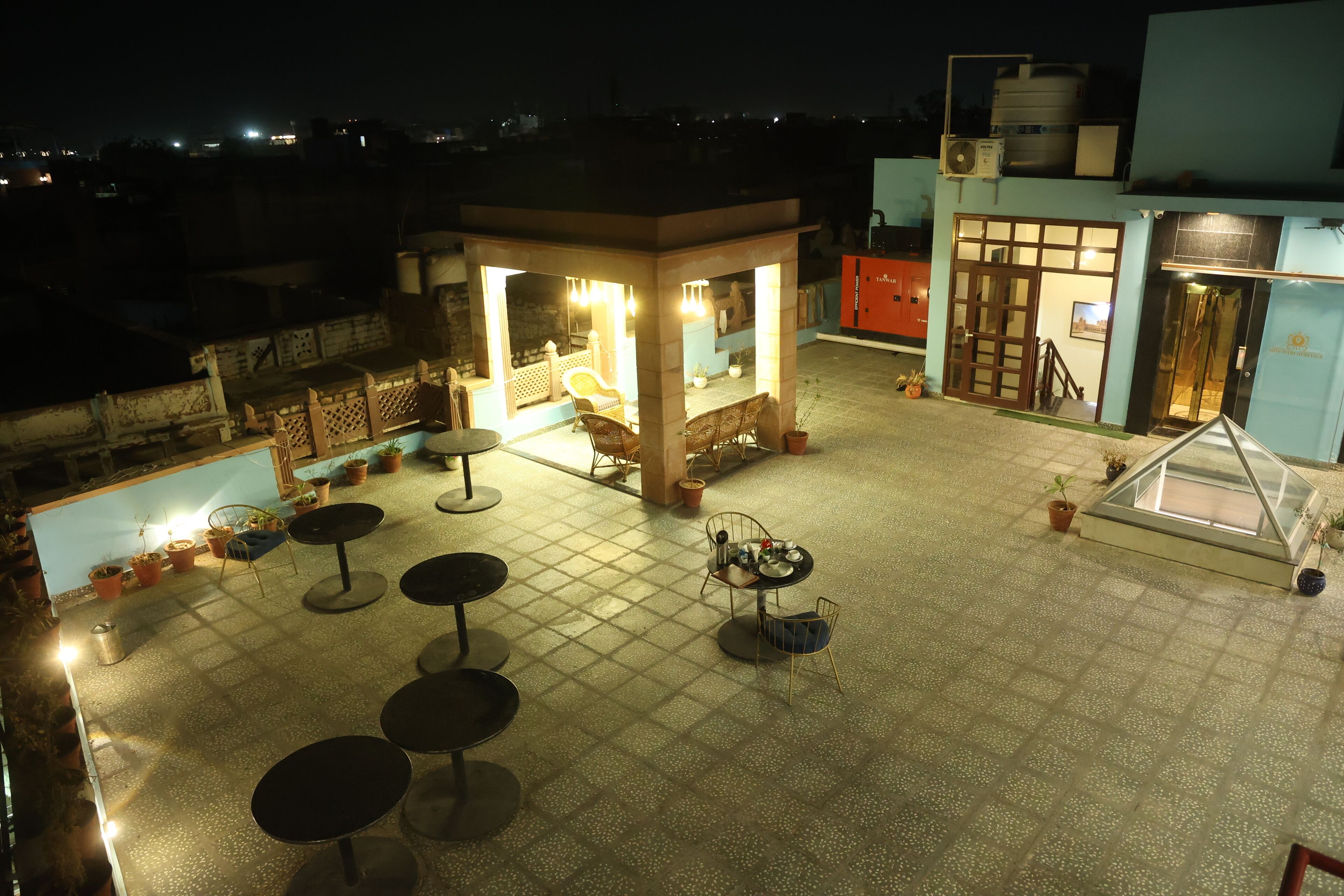 A rooftop terrace with seating areas, a small covered seating area, and a water tank on the building.