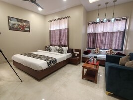 A hotel room with a bed, a sofa, a coffee table, and a ceiling fan.