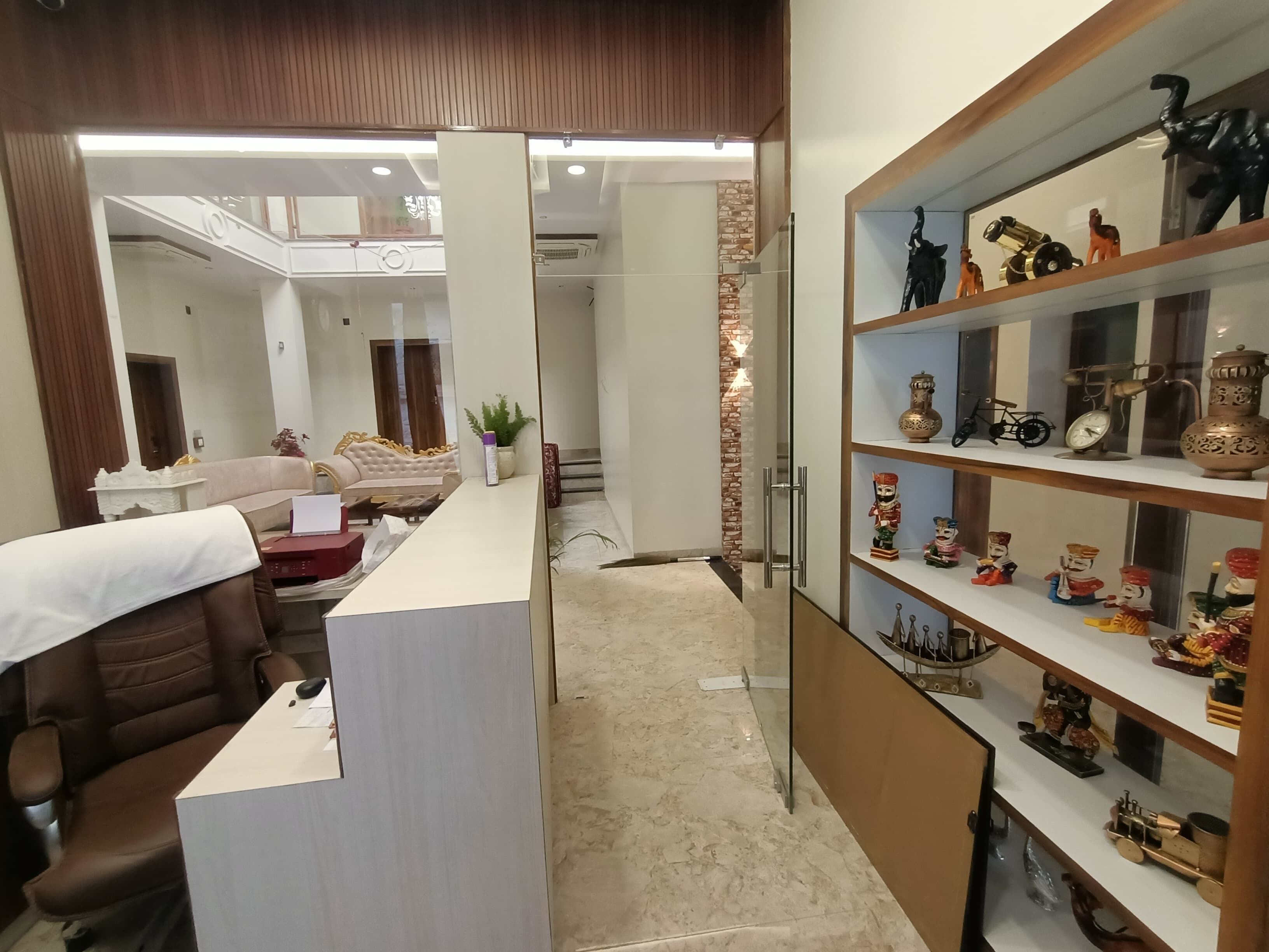 A modern hotel lobby with a reception desk, seating area, and a display of decorative items.