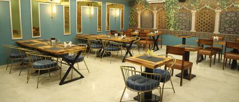 A restaurant with multiple tables and chairs, ceiling fans, and decorative wall panels.
