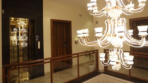 Eine Hotelhalle mit einer prunkvollen Kronleuchter, einem Glastür-Eingang und einer Holztür.