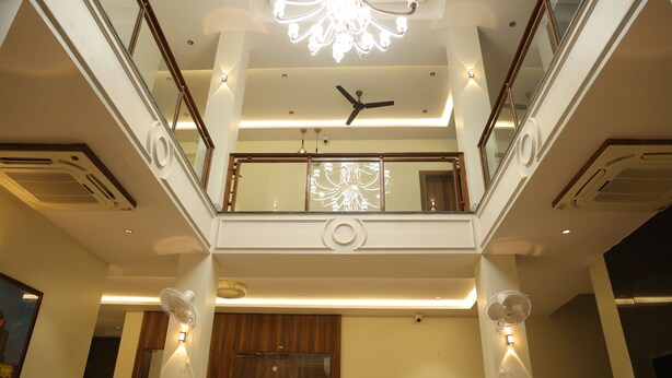 Ein mehrgeschossiges Interieur mit einer zentralen Treppe, Glasgeländern und einem Chandelier.
