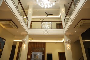 Un interno su più livelli con una scala centrale, ringhiere in vetro e un lampadario.