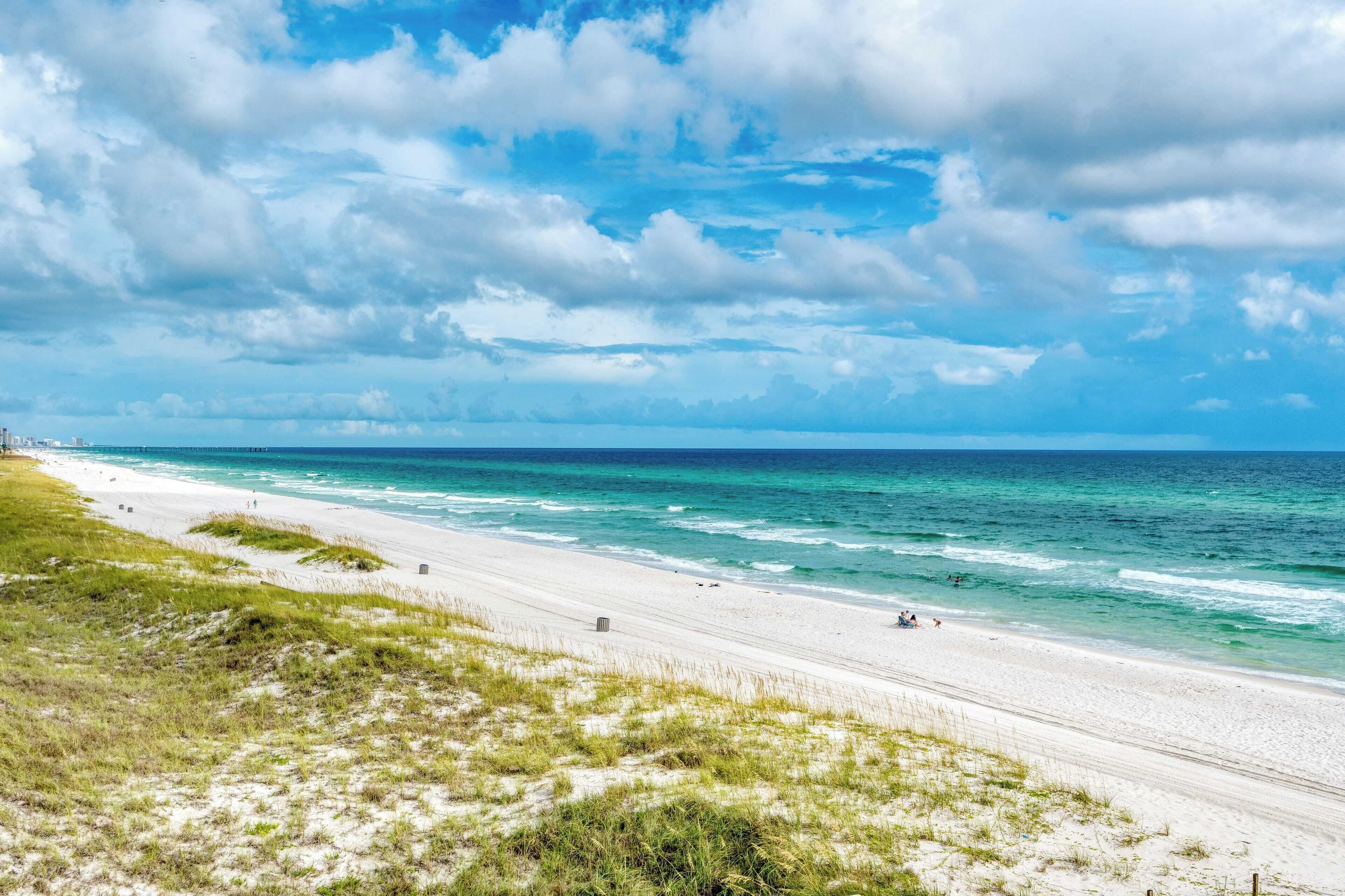 A beach with white sand, ocean waves, and a clear sky.