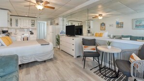 Ett modernt hotellrum med en säng, ett skrivbord, en TV och en sittgrupp med stolar och ett litet bord.