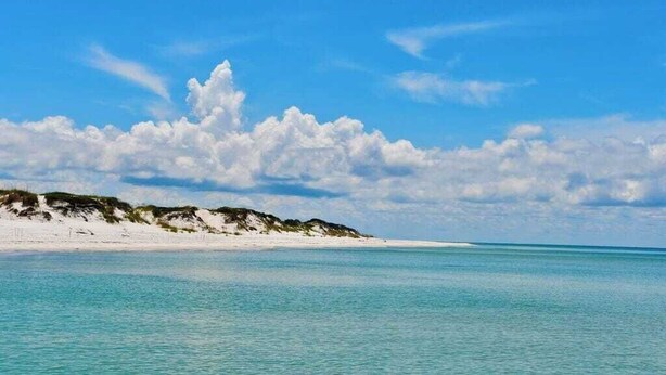 En strand med kristallklart, turkosfärgat vatten och vit sand.