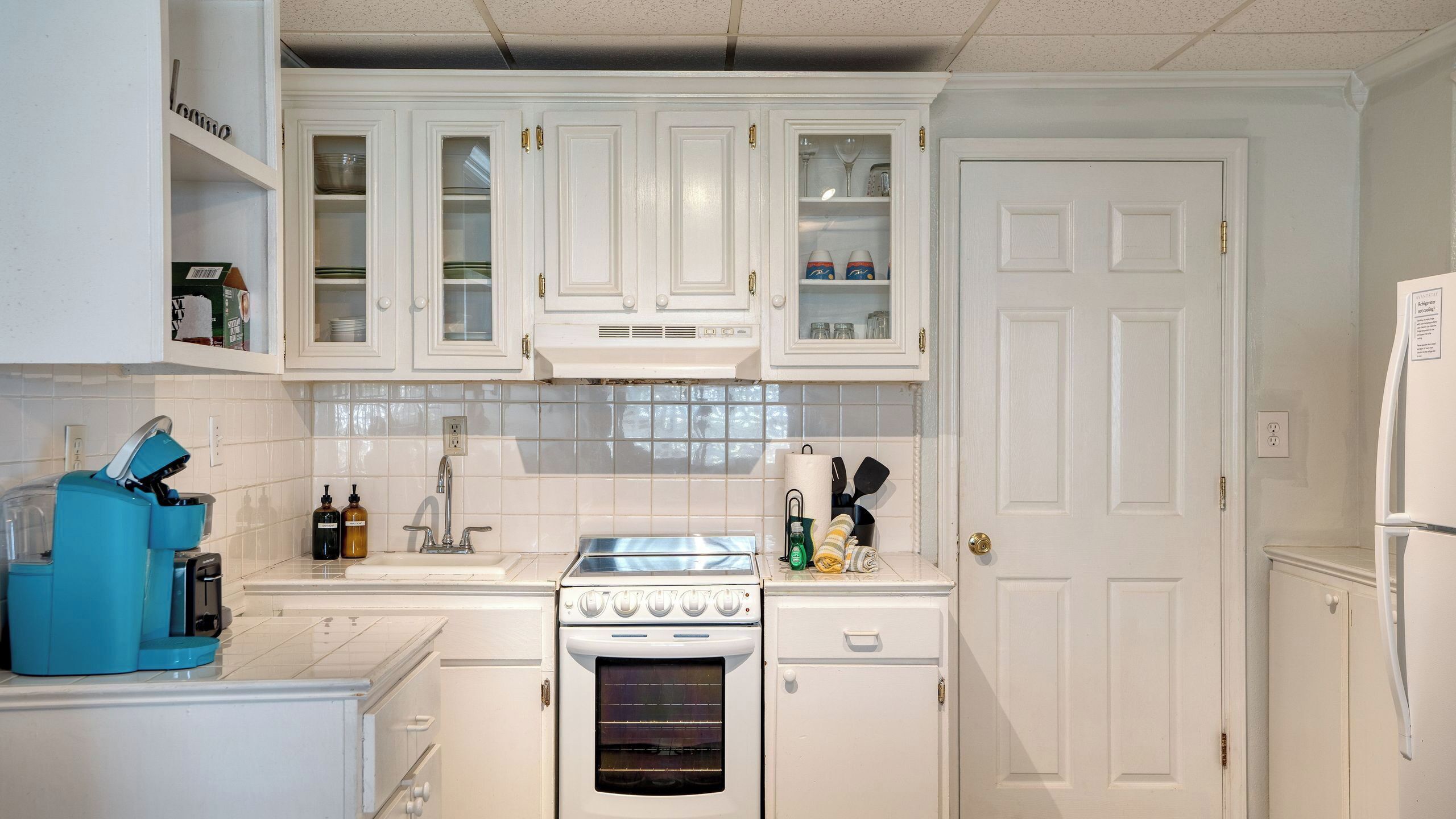 A kitchen with white cabinets, a stove, and a refrigerator.