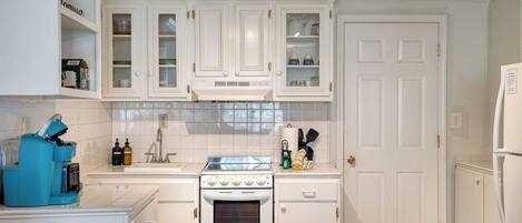 A kitchen with white cabinets, a stove, and a refrigerator.