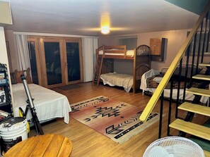 A room with a bunk bed, a wooden table, a fan, and a staircase.