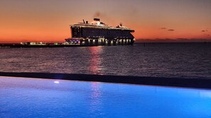 A cruise ship docked at a pier with a pool in the foreground.