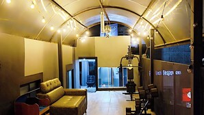 Un intérieur moderne avec un plafond incurvé, un coin salon comprenant un canapé et des fauteuils, et une porte visible donnant sur une autre pièce.