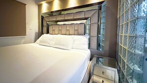 Une chambre à coucher moderne avec un grand lit, une table de chevet et un miroir.