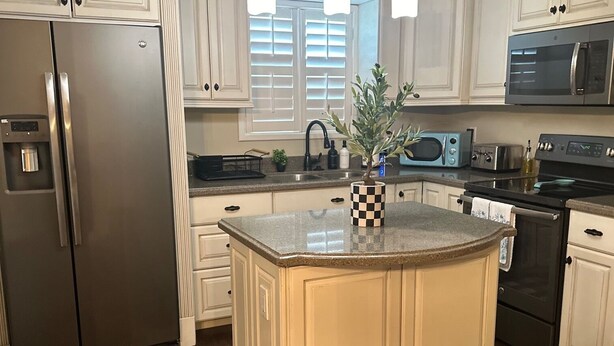 A modern kitchen with white cabinetry, stainless steel appliances, and a central island.