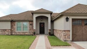 A two-story house with a stone facade, a front door with a wreath, and a garage door.
