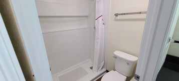 Un baño pequeño y funcional con ducha, inodoro y perchero.