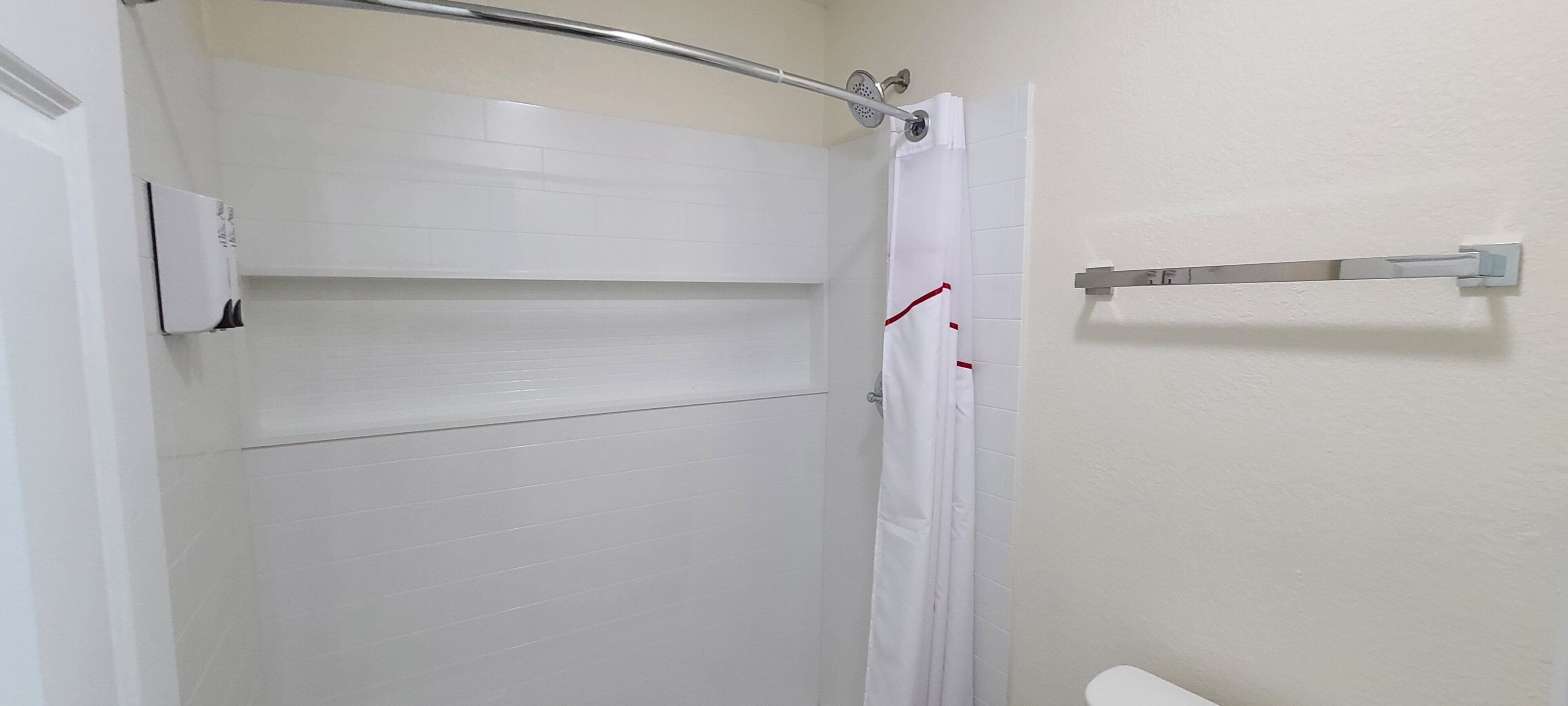 Ein Badezimmer mit weißen Fliesen, einer weißen Duschvorhang und einem Handtuchhalter.