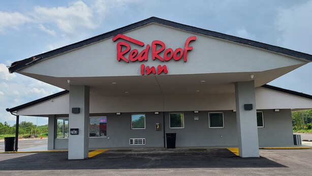 A Red Roof Inn with a flat roof, a covered parking area, and a clear sky. - Red Roof Inn Byron (Byron)