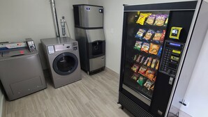 Une buanderie équipée d’un lave-linge, d’un sèche-linge et d’un distributeur automatique de collations.
