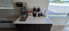 A coffee station with a coffee machine, two coffee makers, and condiments. - Red Roof Inn Byron (Byron)
