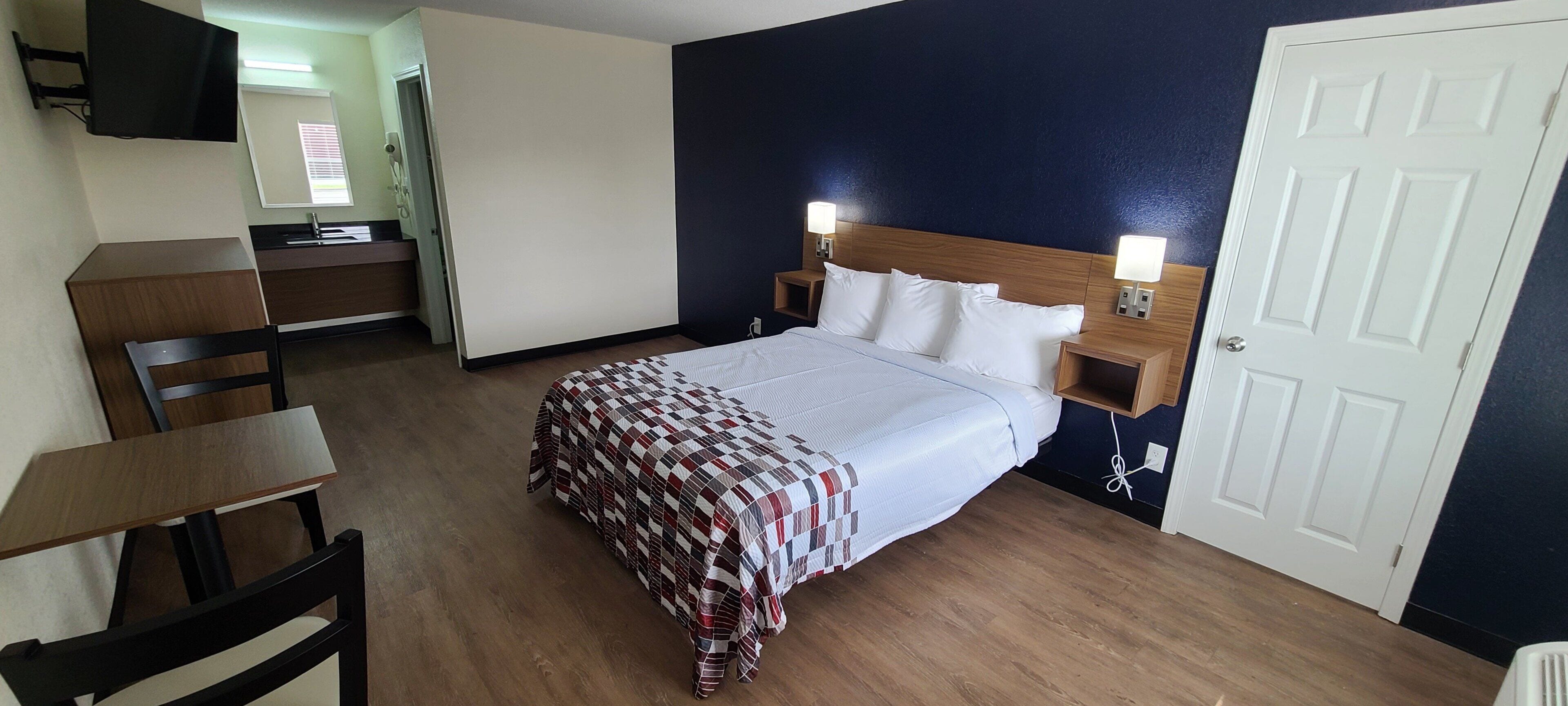 Ein Hotelzimmer mit Bett, Nachttischen, Schreibtisch und Stuhl.