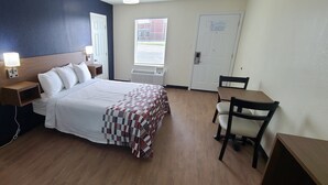 Une chambre d’hôtel avec un lit, des tables de chevet, un bureau et une chaise.