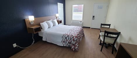 Una habitación de hotel con cama, mesitas de noche, un escritorio y una silla.
