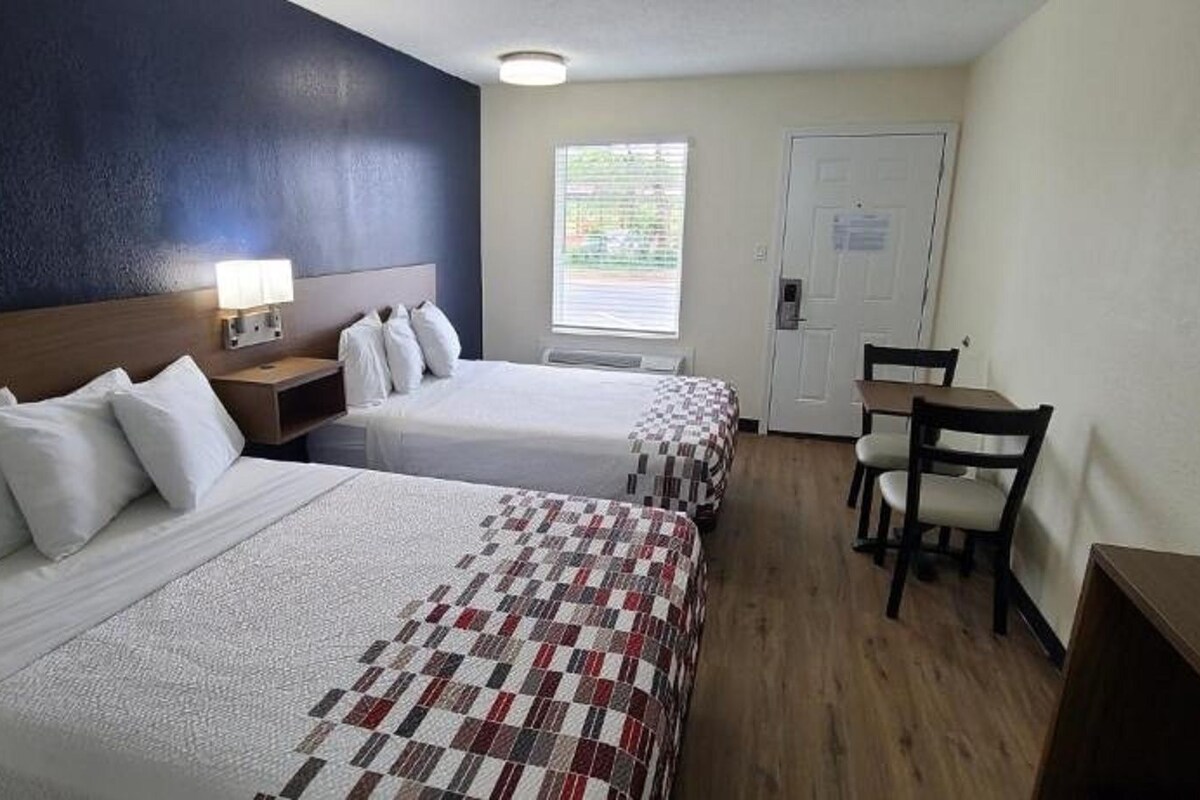 Hotellihuone, jossa on kaksi sänkyä, työpöytä ja tuoli.