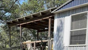 A covered outdoor seating area with a wooden bench and a table, adjacent to a building with a window and a door. - Casita on the Ranch-wildlife,sunsets, stars, relax (Spring Branch)