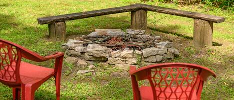 Un espacio de estar al aire libre rústico, con una chimenea de piedra y bancos de madera.