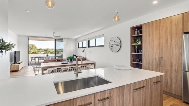 Une cuisine moderne dotée d’un îlot central, de meubles en bois et de luminaires suspendus.
